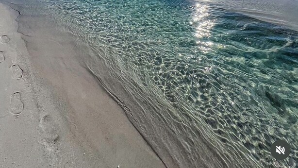 A beach with clear water and a bright sun.