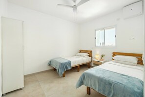 Een slaapkamer met twee eenpersoonsbedden, een kledingkast, een plafondventilator en een raam met uitzicht.