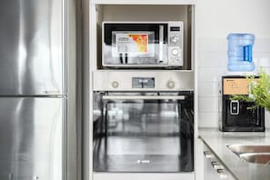 A kitchen with a microwave, oven, and water dispenser.