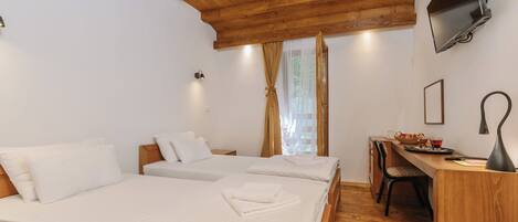 Habitación de hotel con dos camas, techo de madera, televisor montado en la pared y escritorio con una silla.