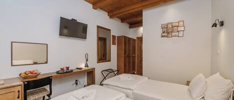 A hotel room with two beds, a wooden ceiling, a TV, a mirror, and a small desk with a bowl of fruit.