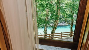 Eine Holztreppe führt zu einem Balkon mit Blick auf einen Strand und Bäume.
