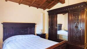A bedroom with a wooden bed frame, a nightstand, a dresser with a mirror, and a radiator. - Amazing apartment in Subbiano (Subbiano)