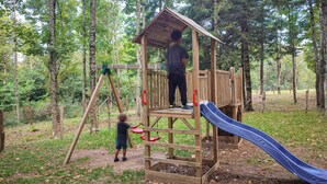 A wooden play structure with a slide and a swing set in a wooded area. - Amazing apartment in Subbiano (Subbiano)
