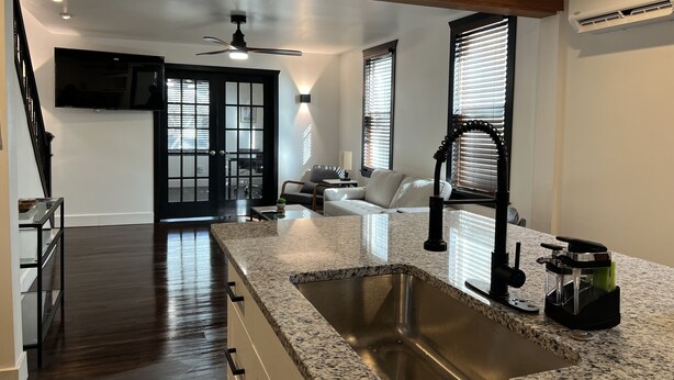 A modern kitchen with a granite countertop, stainless steel sink, and a built-in range hood. - Pet Friendly Spacious Luxe Corner House for Professionals - Left Side (Kingston)