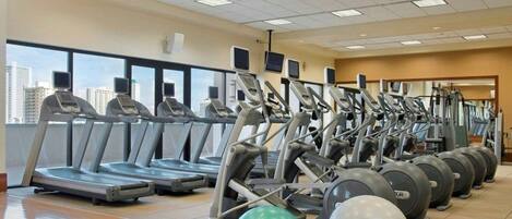 A gym with treadmills, elliptical machines, and exercise balls.
