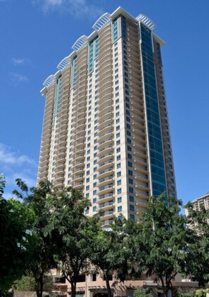 A tall, multi-story hotel with balconies and a clear sky. - Waikiki | Partial Ocean View | Pool & Beach | 2BR Plus (Honolulu Oahu)