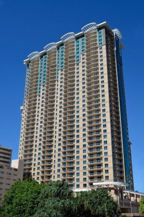 A high-rise building with multiple balconies and a clear sky. - Waikiki | Partial Ocean View | Pool & Beach | 2BR Plus (Honolulu Oahu)