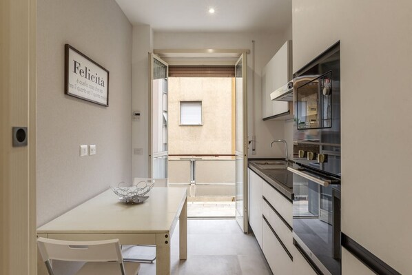 A compact kitchen with modern appliances, a dining area with a table and chairs, and a small window.