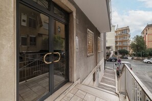 A building entrance with a glass door, a metal gate, and a staircase leading to a parking area.