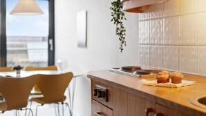 Eine moderne Küche mit Holzschränken, einer Spüle aus Edelstahl und einer hängenden Pflanze.