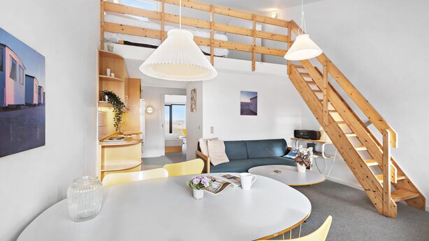 Ein kompakter Wohnraum mit Essbereich, einer Couch, einer Treppe und einer Küchenzeile.