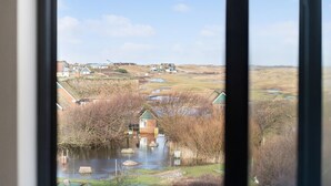 Ein Blick auf eine ländliche Landschaft mit Teich, Häusern und einer Hügelkette im Hintergrund.