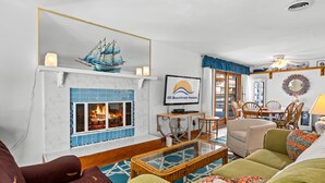 A living room with a fireplace, a television, and a dining area with chairs. - ⭐️Fountain Head Beach Bungalows steps to Beach Pool⭐️ (Ocean City)