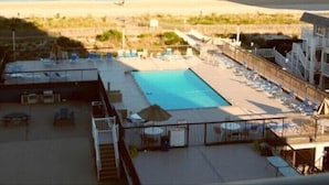 A pool area with lounge chairs and umbrellas, overlooking a beach. - ⭐️Fountain Head Beach Bungalows steps to Beach Pool⭐️ (Ocean City)