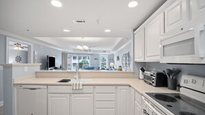 A modern kitchen with white cabinetry, a dishwasher, a stove, and a microwave. - Tybee Beachfront Condo, 2 Pools & Restaurant, 1–3BR Flexibility, Turtle Time (Tybee Island)
