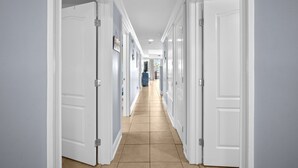 A hallway with white doors, beige flooring, and a view into a room at the end. - Tybee Beachfront Condo, 2 Pools & Restaurant, 1–3BR Flexibility, Turtle Time (Tybee Island)