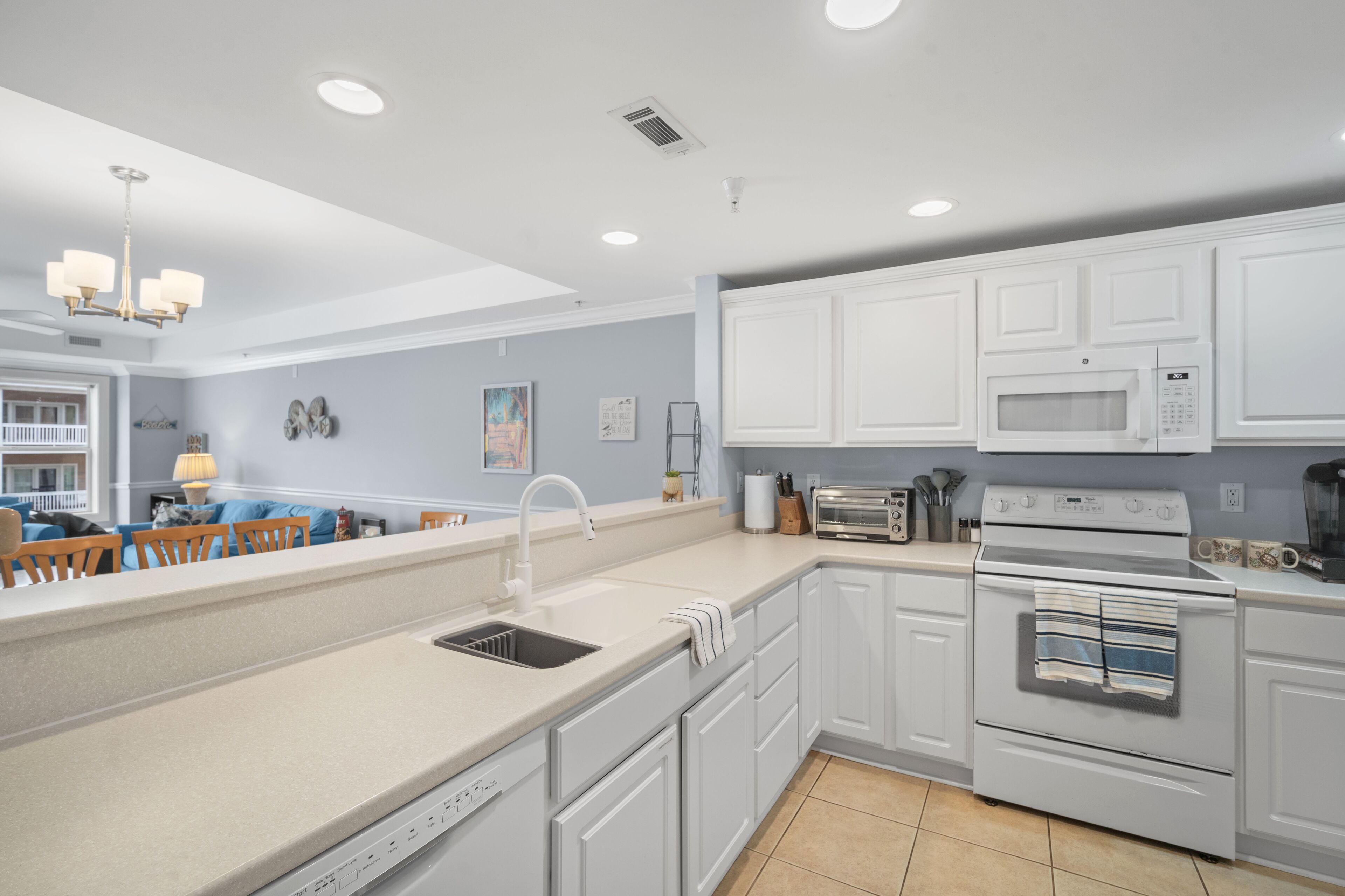 A modern kitchen with white cabinets, a built-in oven, a microwave, and a dishwasher.
