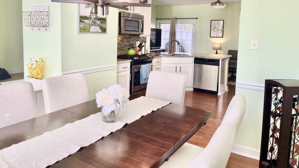 A dining area with a wooden table, white chairs, and a vase of flowers. - Townhome in Village of 5 Points, 3BDR 2.5BA Sleeps 6-8. Saturday-Saturday (Lewes)