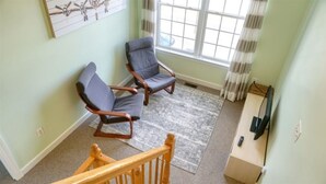 A room with two armchairs, a wooden staircase, a television, and a window with curtains. - Townhome in Village of 5 Points, 3BDR 2.5BA Sleeps 6-8. Saturday-Saturday (Lewes)