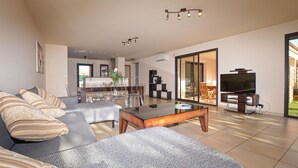 Ein modernes Wohnzimmer mit einer Couch, einem Couchtisch und einem Fernseher. Es gibt einen Essbereich mit Stühlen und einem Tisch.
