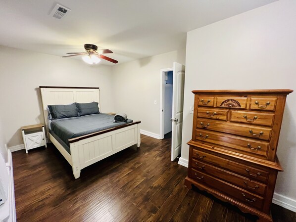 Un dormitorio con cama, cómoda y ventilador de techo.