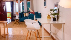 Una sala de estar moderna con un sofá azul, un sillón blanco y una mesa de comedor.