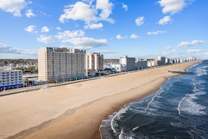 A coastal hotel with multiple high-rise buildings, a sandy beach, and a view of the ocean.