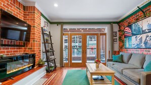 Un salon avec un mur en briques, un téléviseur à écran plat, une table basse en bois et un canapé.