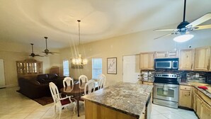 A spacious kitchen with a central island, a dining area with white chairs, and a ceiling fan. - “3bdrm Barn Apt” @ Sunset Pointe (Lincoln)