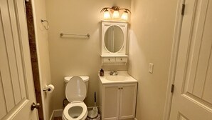 A bathroom with a toilet, sink, and mirror. - “3bdrm Barn Apt” @ Sunset Pointe (Lincoln)