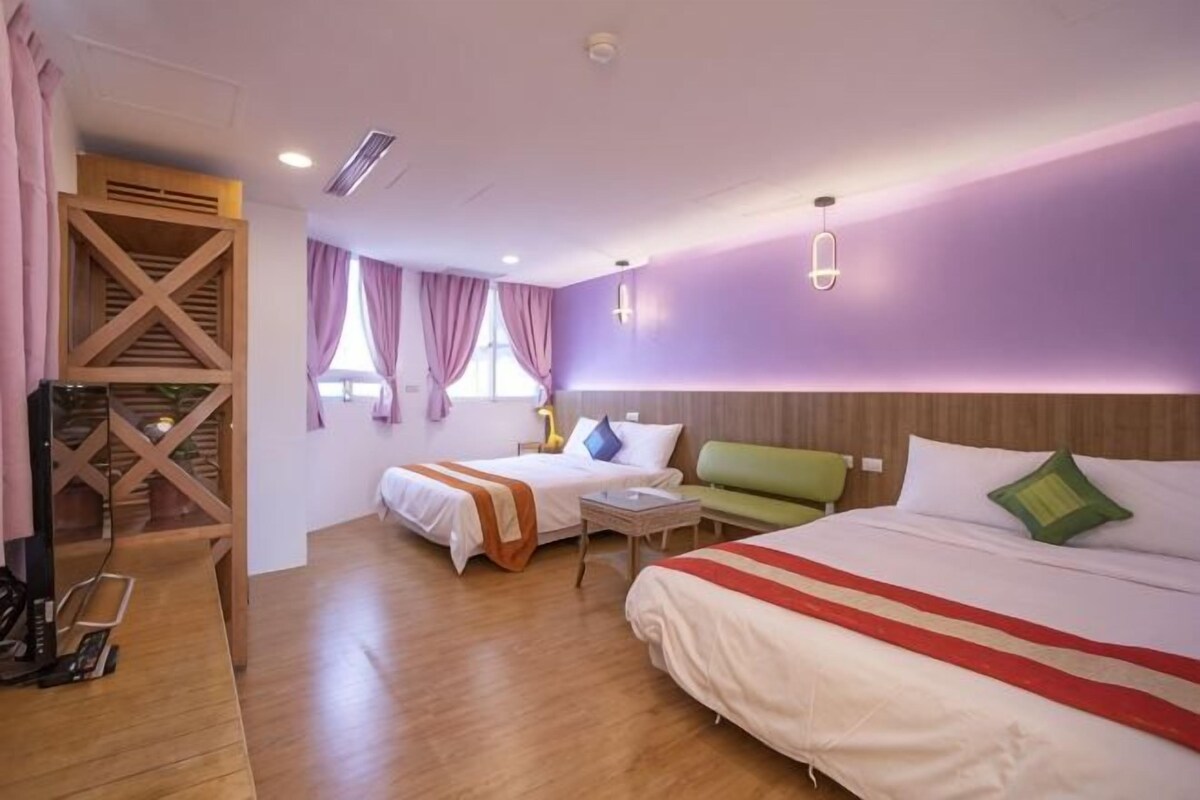 A hotel room with two beds, a sofa, a small table, and a wooden structure.