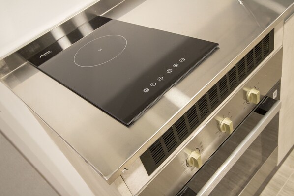 A modern induction cooktop with a sleek black surface and a circular control panel.