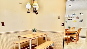 Une pièce d’angle avec une table et un banc en bois, une plante en pot et un mur décoré d’autocollants représentant des poissons.