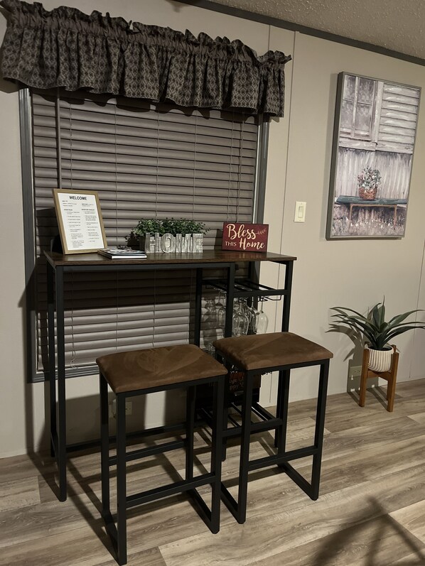 A reception desk with a welcome sign, a 'Bless this Home' sign, and a framed picture on the wall.
