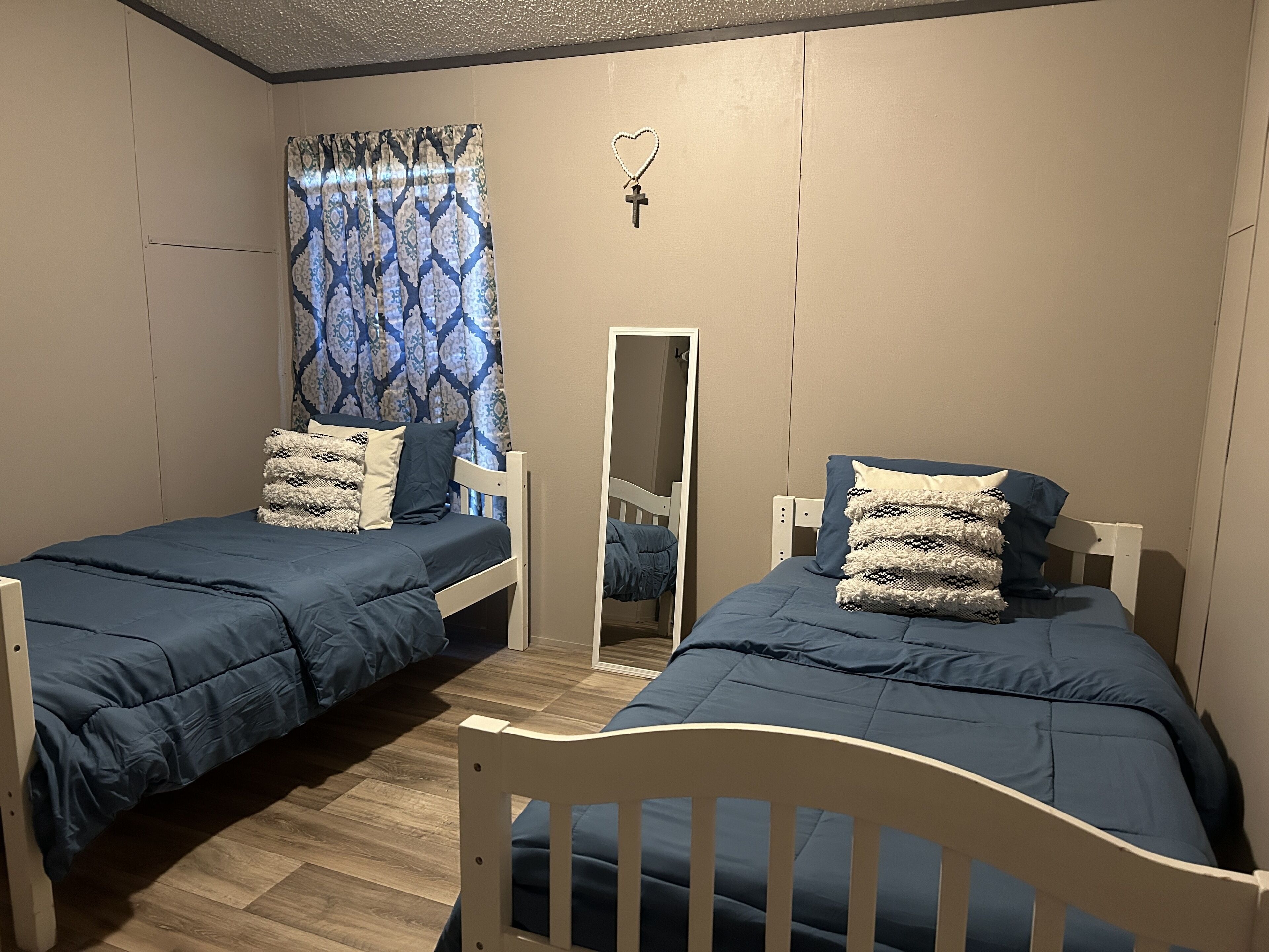 A bedroom with two single beds, a mirror, and a patterned curtain.