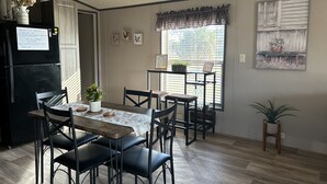 A dining area with a wooden table, black chairs, and a potted plant.