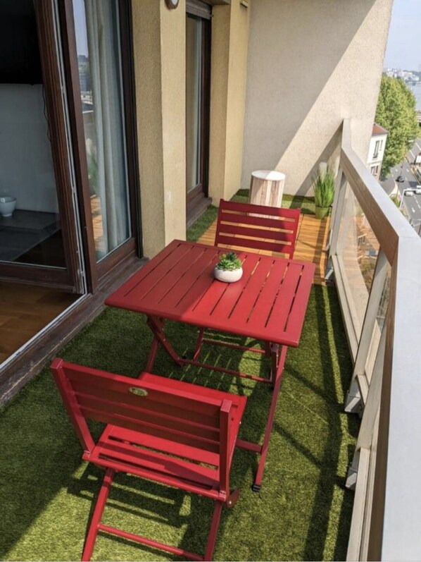 Relax in this outdoor seating area with a table and chairs, surrounded by lush greenery and a beautiful view.