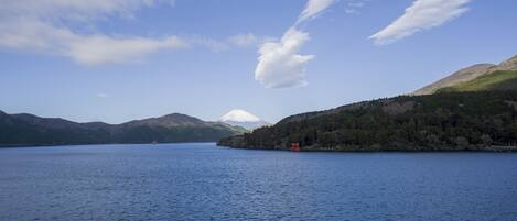 A calm lake with mountains in the background and a small red structure on the right.