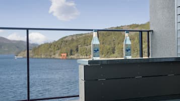 A balcony with two bottles of water, a view of a lake, and a distant red structure.