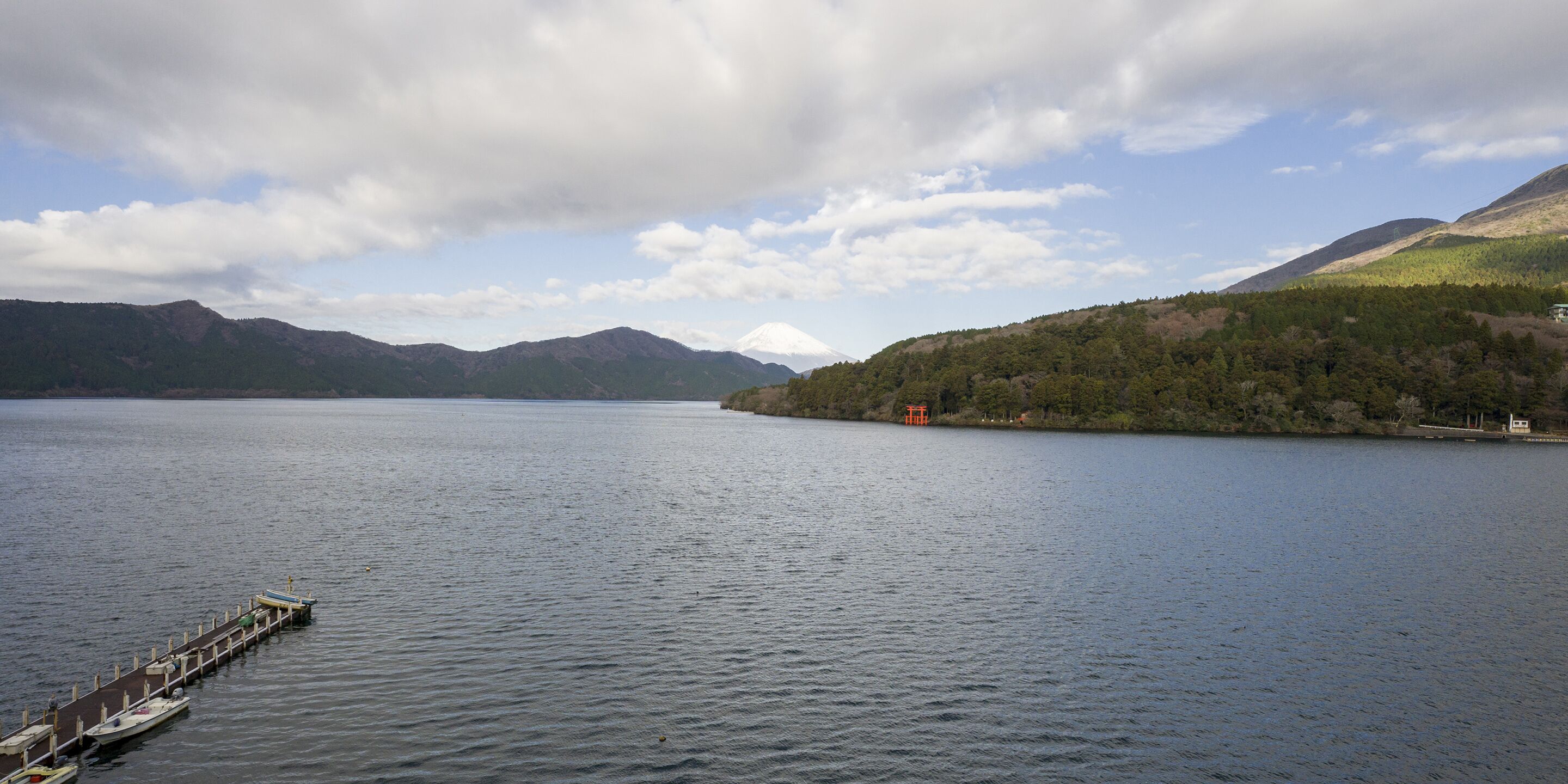 Un lac paisible, avec un quai et un petit bâtiment sur la rive.