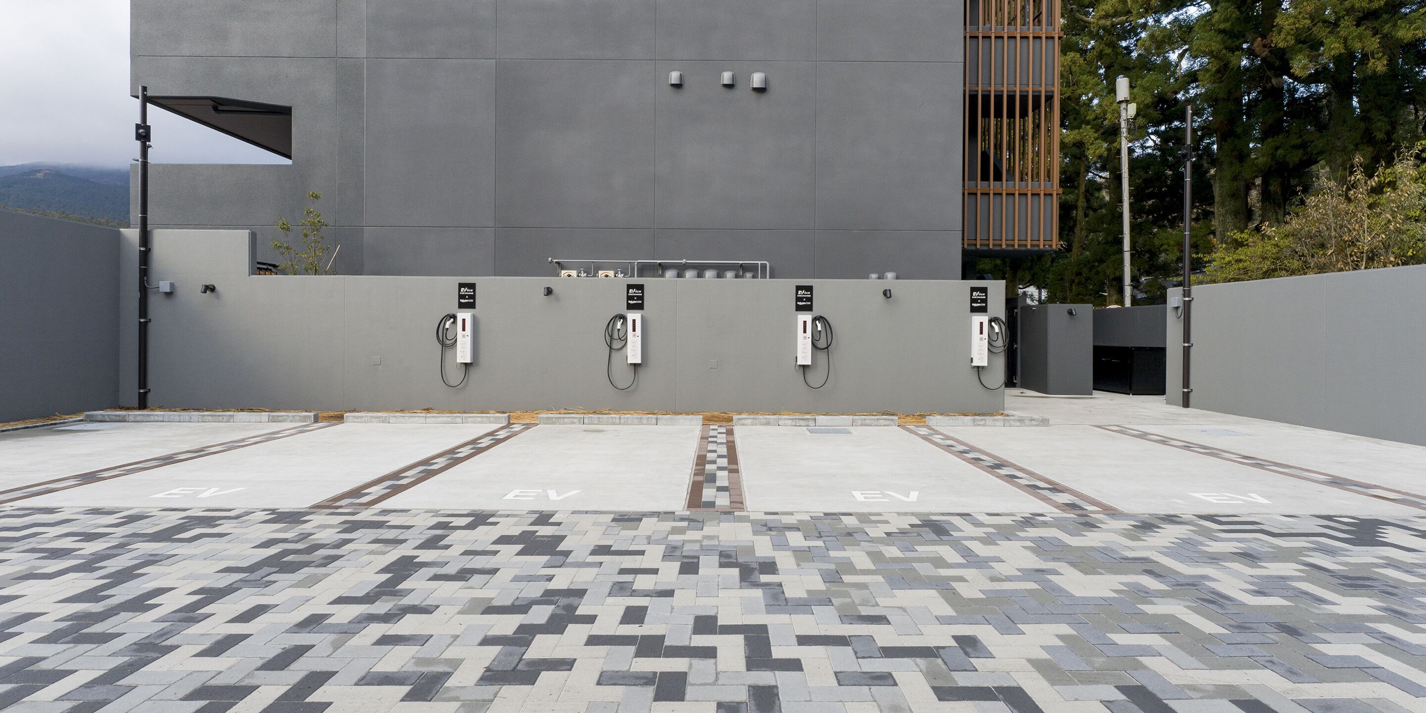 An EV charging station area with a modern building in the background.