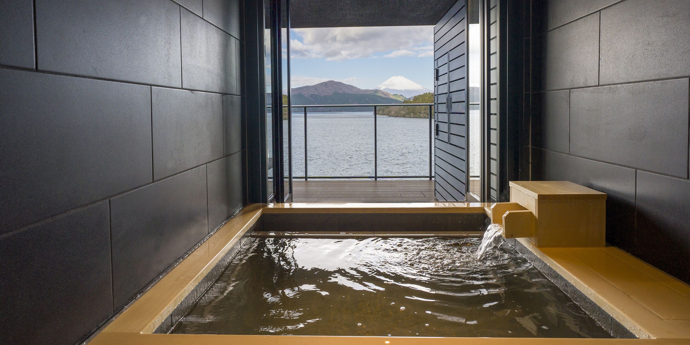 Baño termal con vista a una montaña y un lago.
