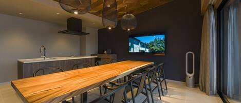 A modern kitchen with a wooden dining table, chairs, and pendant lights.