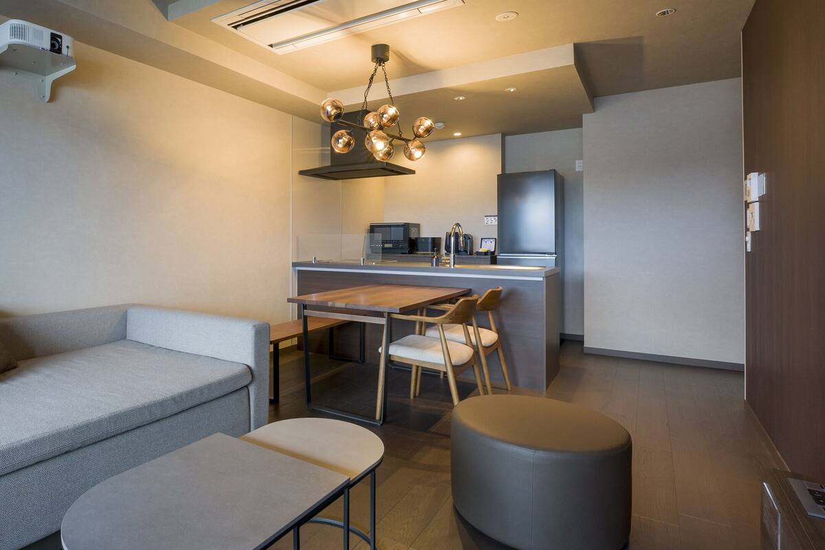 A modern living room with a sofa, a dining table, and a kitchen area in the background.