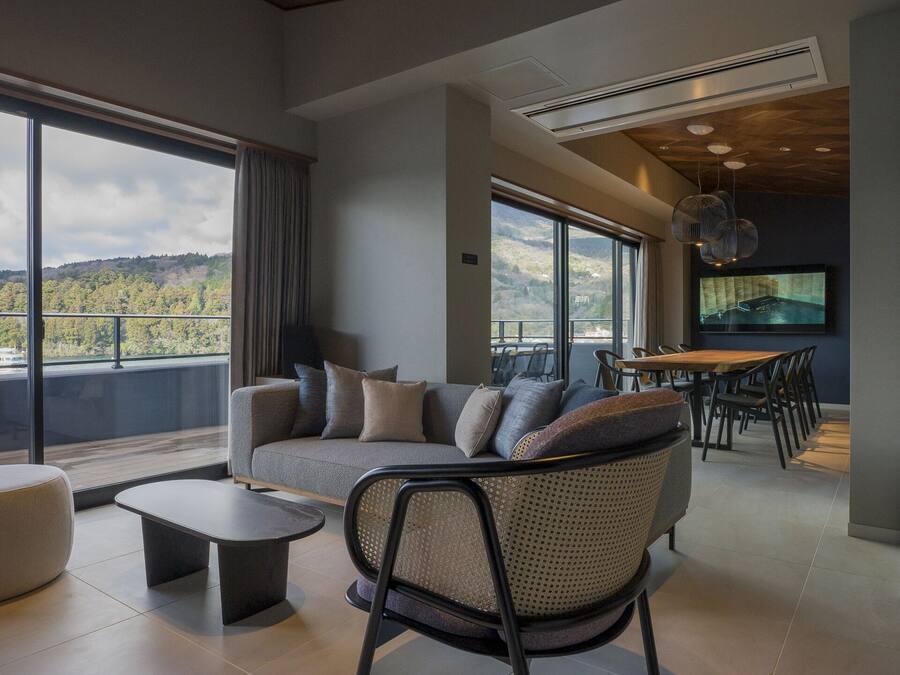 A modern living room with a large window, a sofa, a coffee table, and a dining area.
