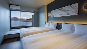 A modern hotel room with a large bed, a view of a mountain, and a painting on the wall.