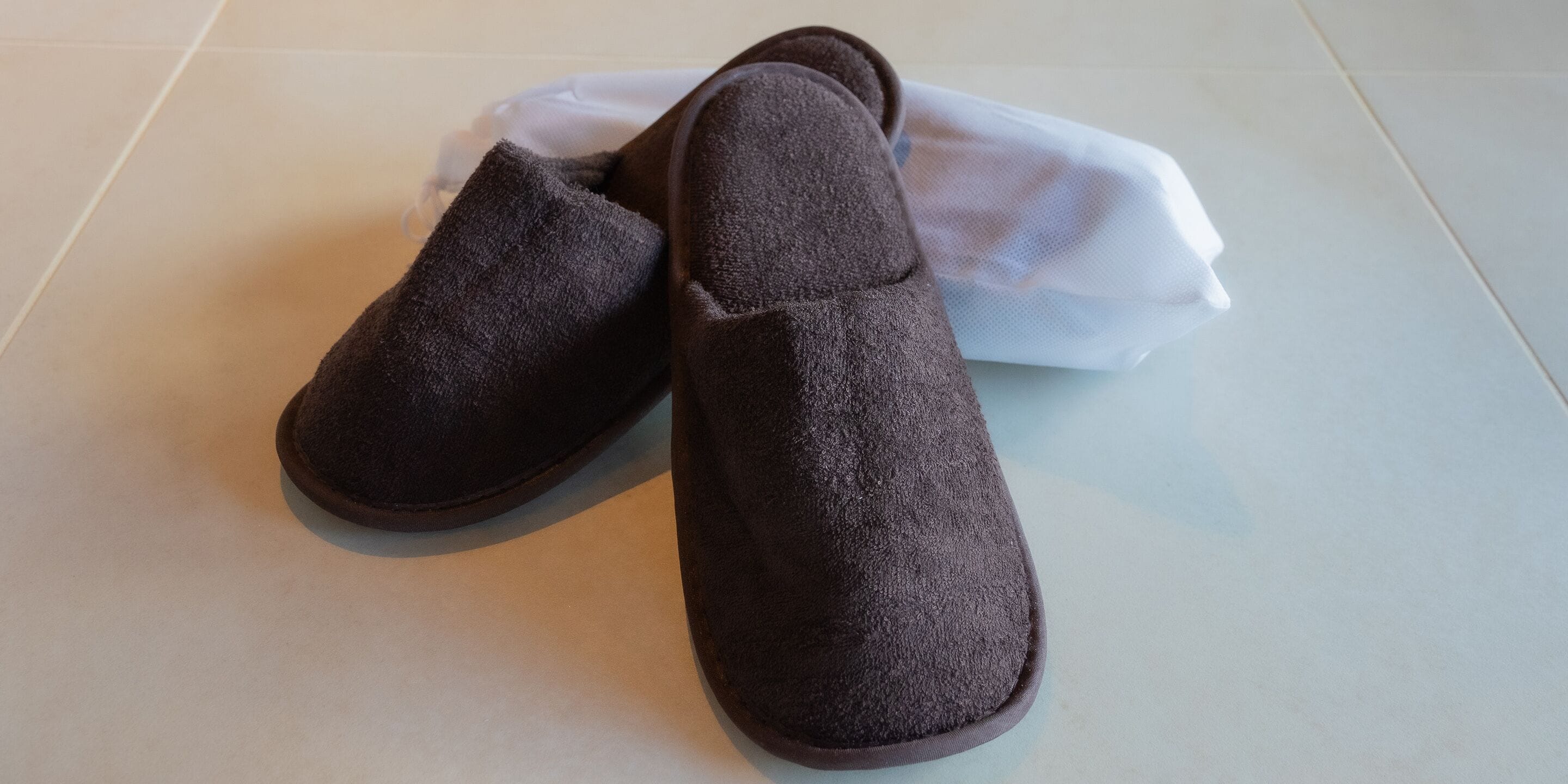 A pair of dark slippers on a light-colored surface.