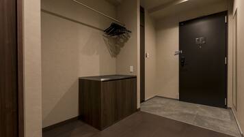 A hallway with a dark wooden cabinet, a coat rack with hanging items, and a dark door with a sign.