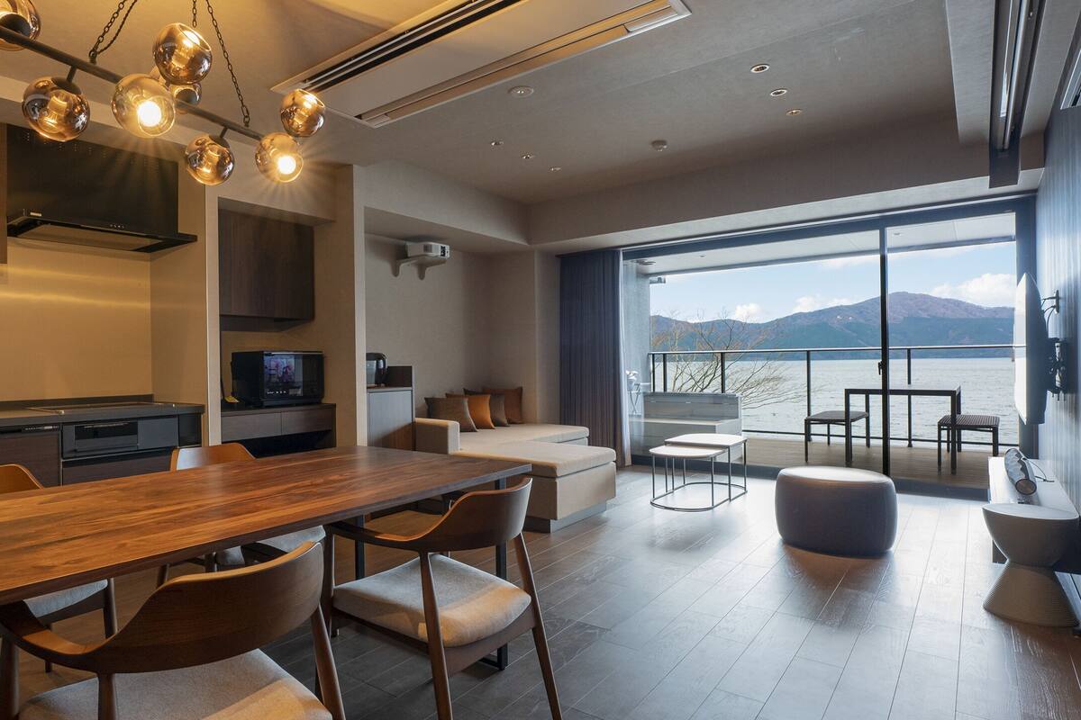 A modern kitchen with a wooden dining table, built-in appliances, and a large window overlooking a scenic view.